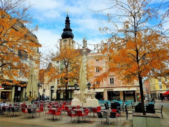 schöner Altstadt-Platz unter herbstlich gelben Bäumen mit Café im Freien