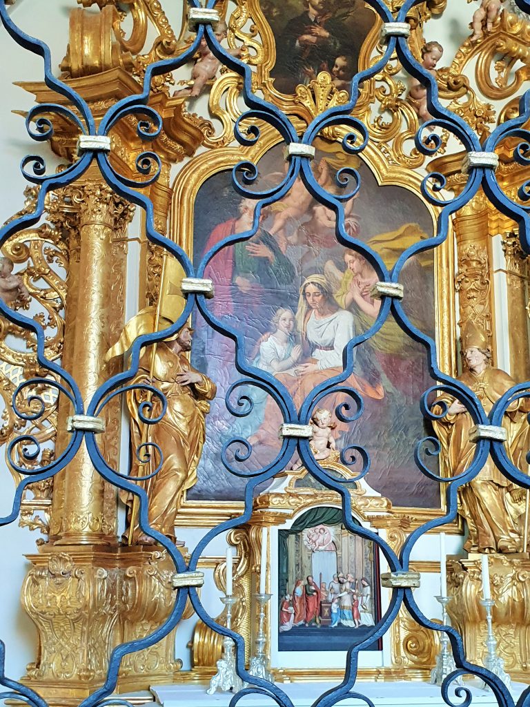 antikes Gittertor aus Schmiedeeisen dahinter Kirchenbild