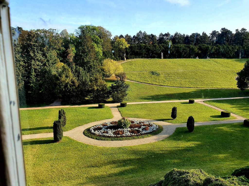 Blick durch Fenster in Schlossgarten mit Brunnen