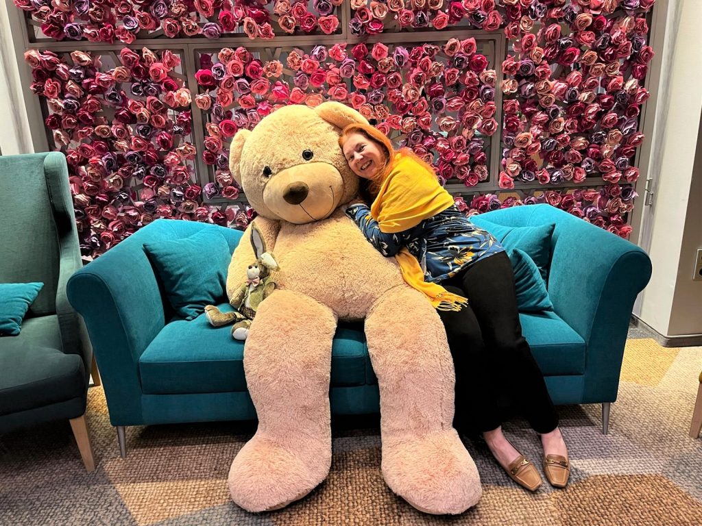 Frau mit Riesen-Teddybär auf Sofa kuschelnd