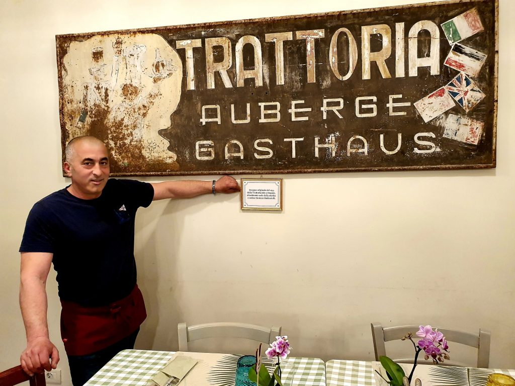Ein Mann zeigt auf die Tafel einer Trattoria in San Marino