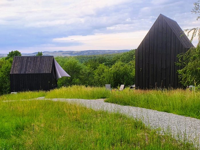 moderne dunkle Holz-Chalets in grüner Hügellandschaft, Ökotourismus Transsilvanien