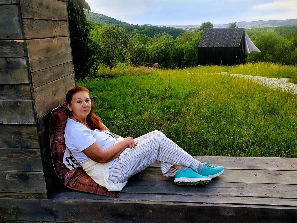 Bloggerin sitzt in Holzrahmen in grüner Landschaft