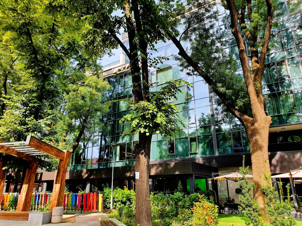 Hotel mit Glasfassade umgeben von hohen grünen Bäumen