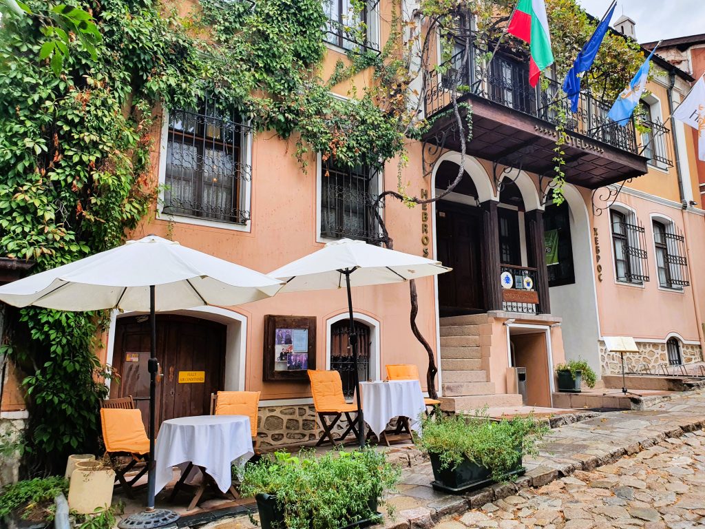 Altstadt Hotel in Plovdiv mit Gästetischen und Sonnenschirmen an der Straße