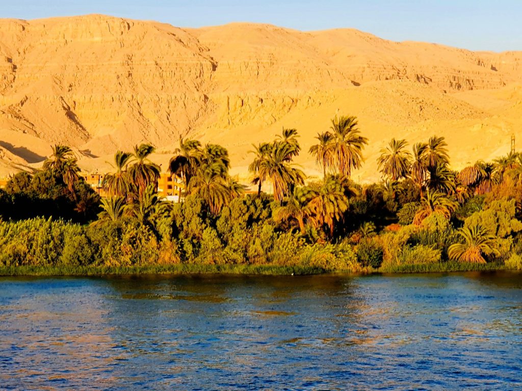 Nil Fluss mit Palmen am Ufer, dahinter Sanddünen, Nilkreuzfahrt Höhepunkte