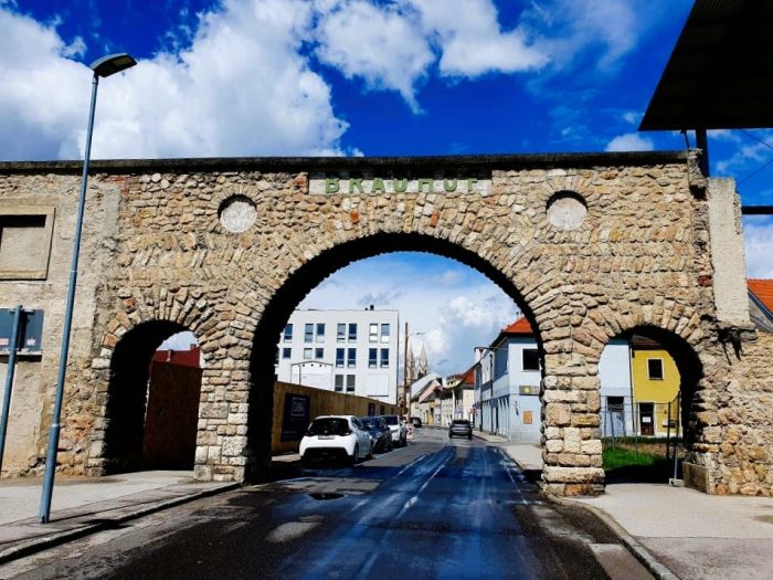 alte Stadtmauer mit Tor, durch das eine Straße führt, Milch & Honig Festival