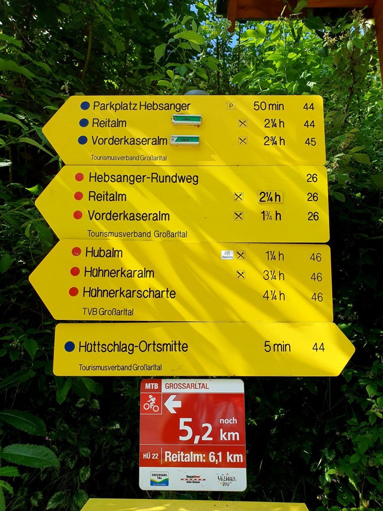 gelbe Wegtafel mit Angabe für Wanderwege im Bergdorf Hüttschlag zu den Almen