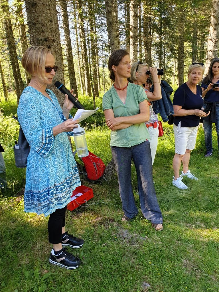 Frauen mit Mikrofon erklärend im Wald stehend