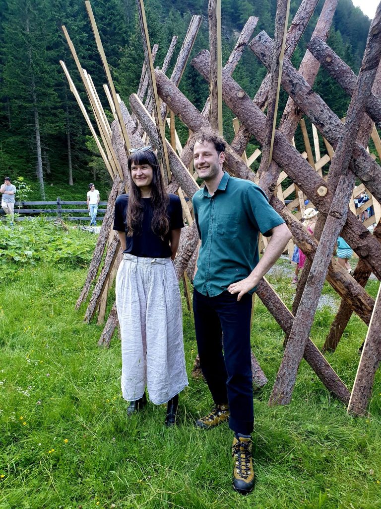 Künstler und Künstlerin vor ihrem Holzzaun-Projekt stehend