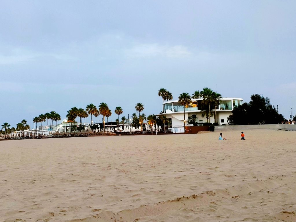 weiter Sandstrand mit Palmen und Beach Club, Strandurlaub Valencia
