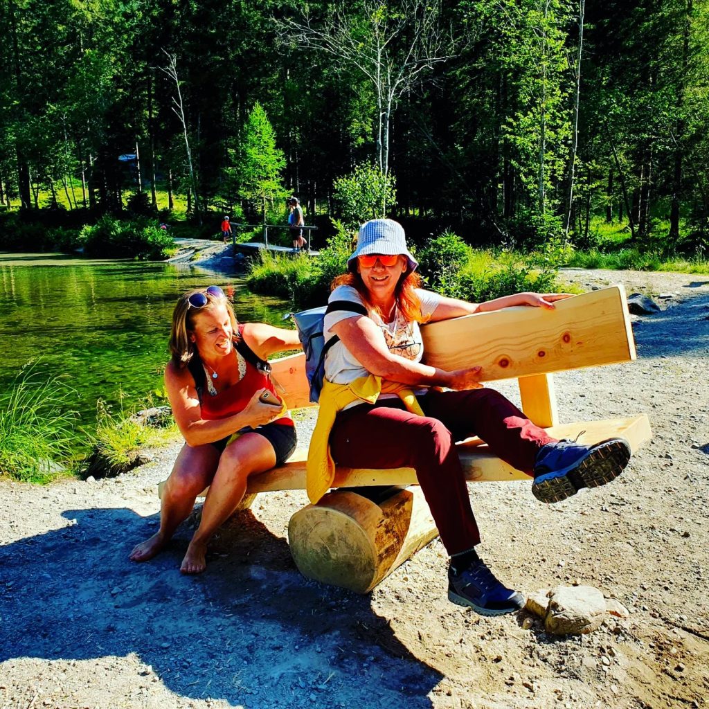 zwei Wanderinnen auf einer Holzwippe sitzend