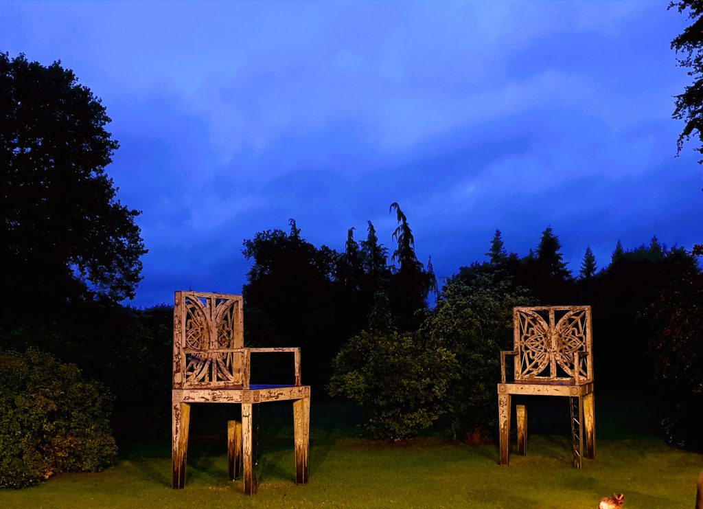 zwei große Sessel als Kunstobjekte in einem Park im Abendlicht