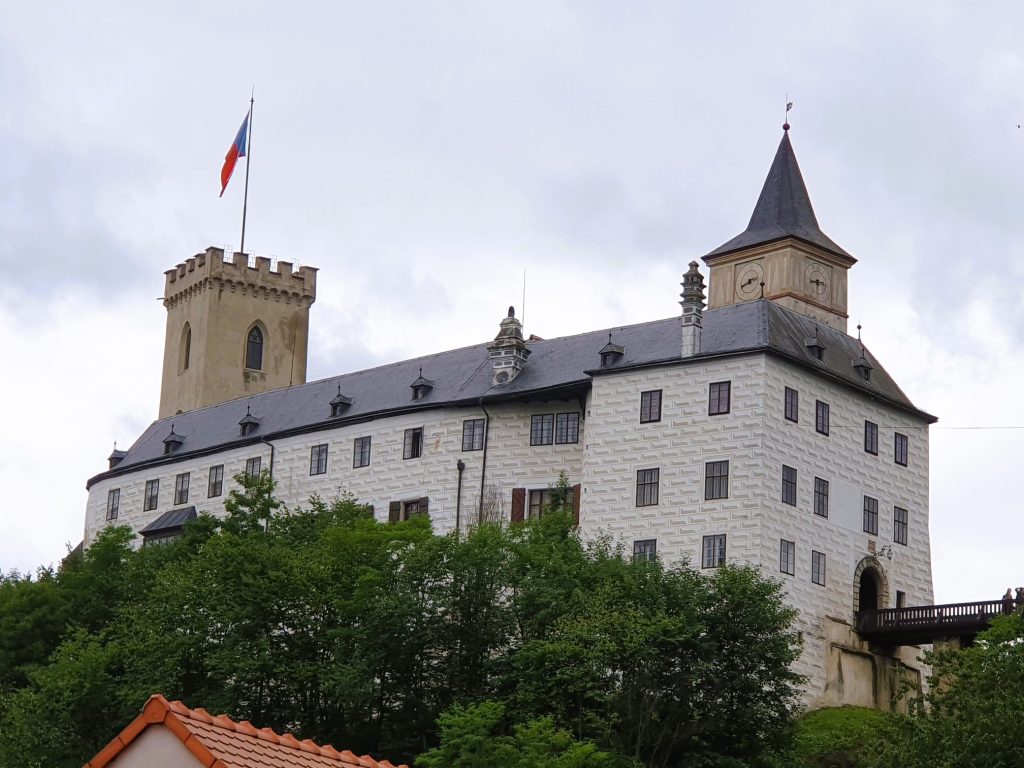 graue Burg mit Türmen und tschechischer Fahne am Turm