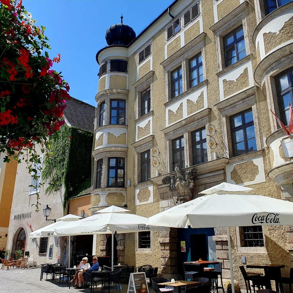 Café mit weißen Sonnenschirmen vor schönem historischem Gebäude