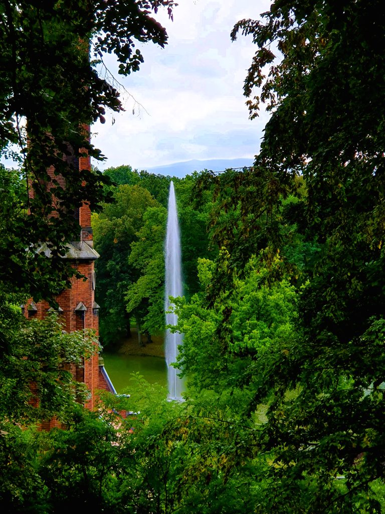 hoher Springbrunnen in grüner Parkanlage