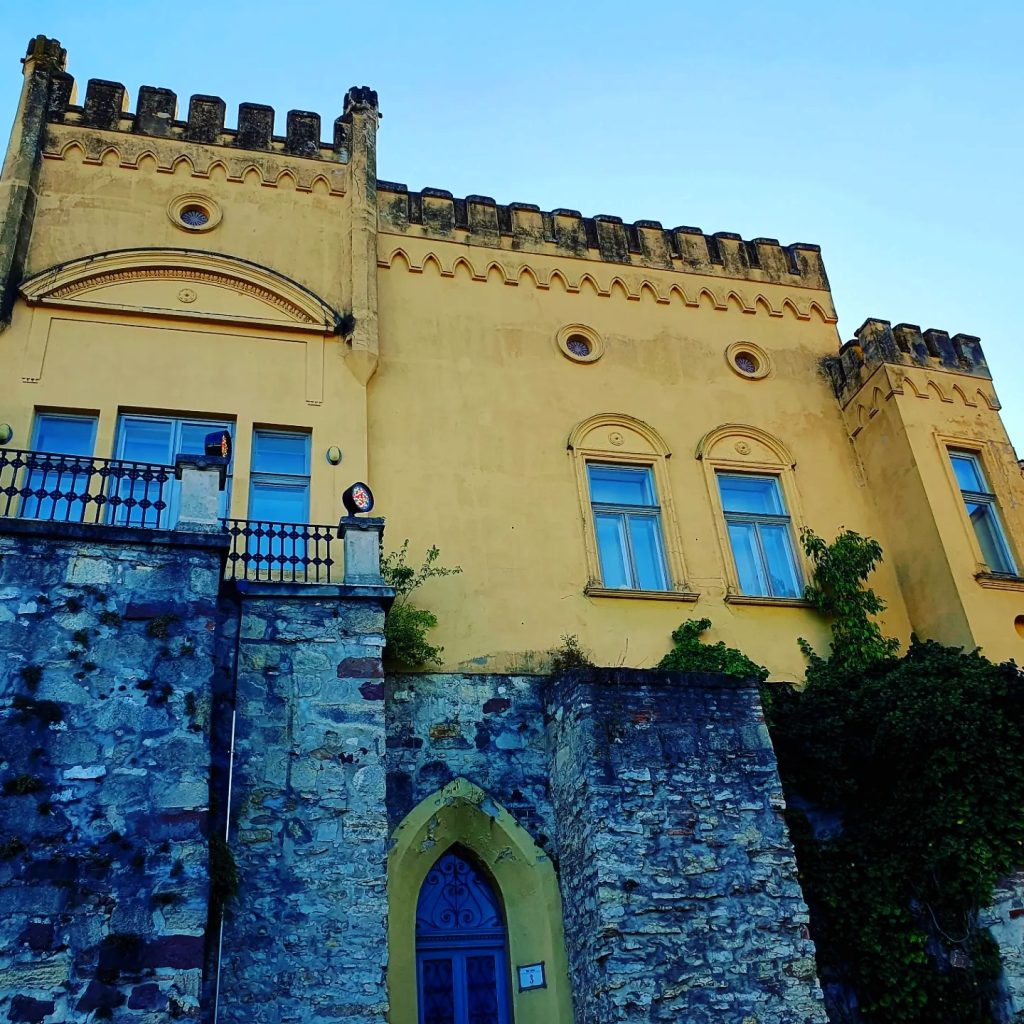 imposanter Bau mit gelber Fassade als Teil einer Burganlage