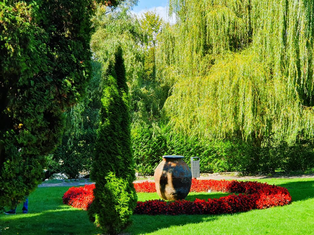 grüner Park mit Weiden und roten Blumen-Beeten