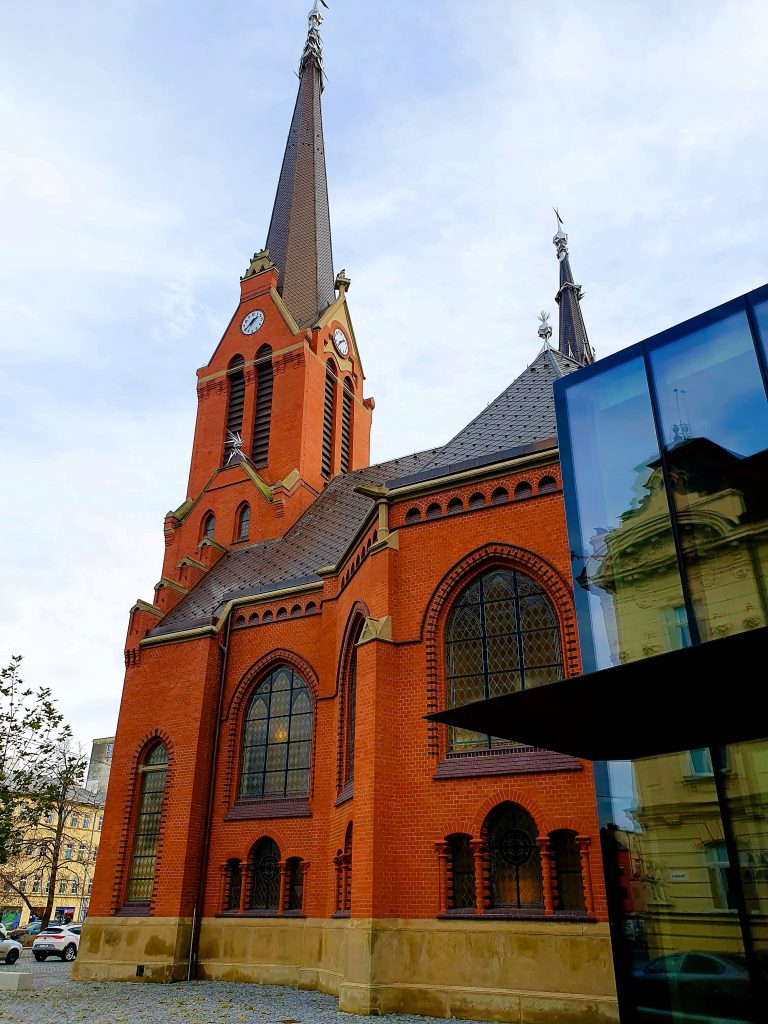 Kirche mit roter Fassade und spitzem Turm