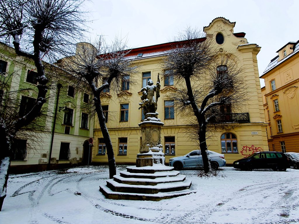 historisches Gebäude mit verschneitem Platz und einem Denkmal, Olmütz Tschechien