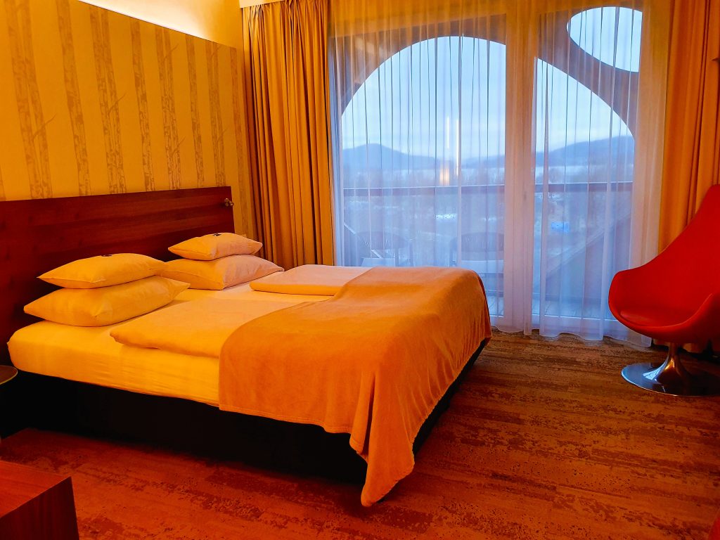 Hotelzimmer mit Doppelbett und Ausblick durch Fenster