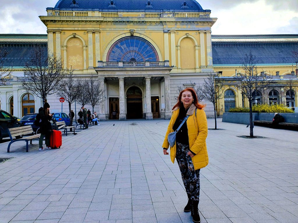 Reisebloggerin steht vor dem historischen Bahnhofsgebäude Budapest Keleti Pu