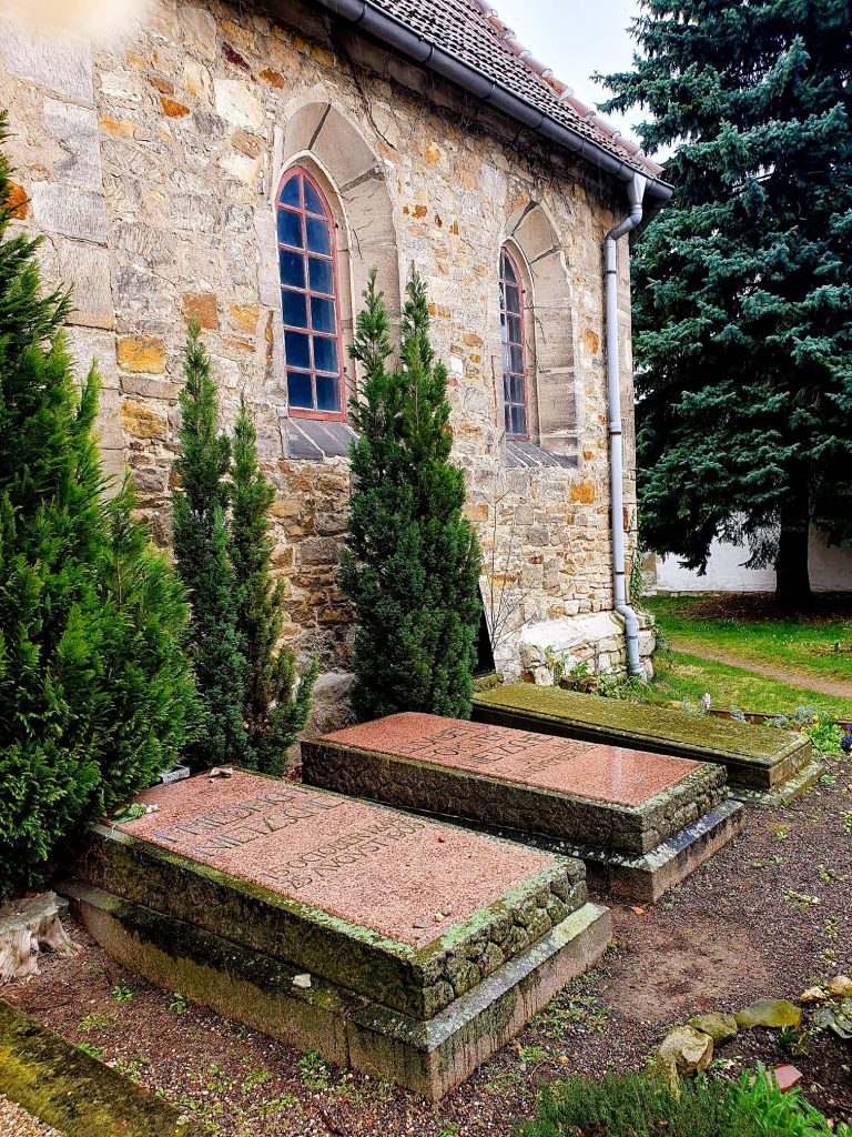 zwei Gräber vor einer steinernen Kirche