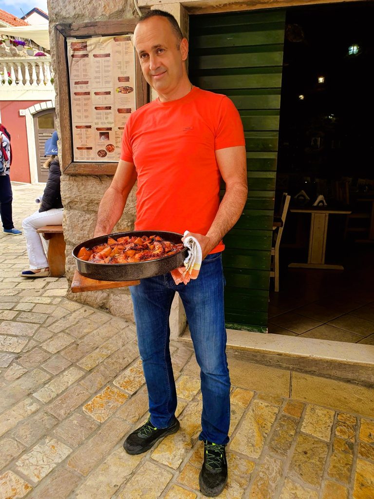 Mann hält eine Pfanne mit einem kroatischen Gericht in der Hand, dalmatische Küche Kroatien Biograd