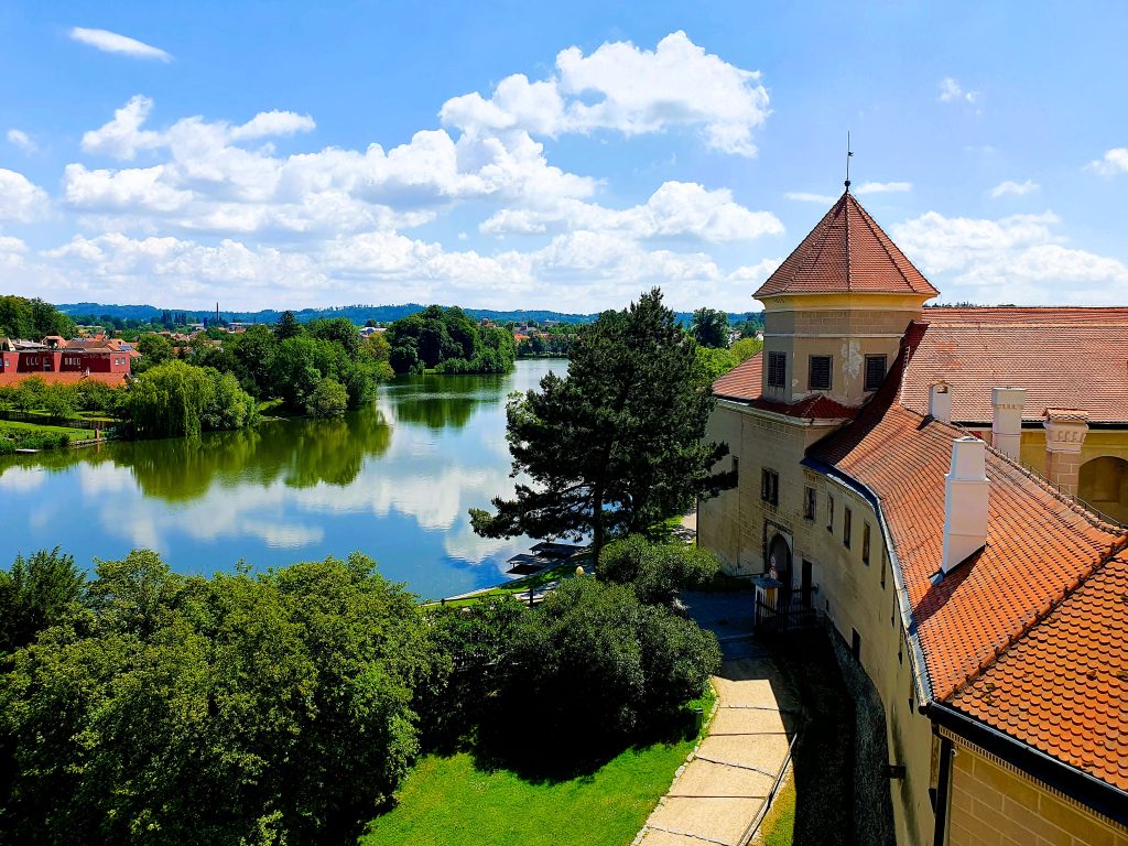 Blick von einem Schloss auf eine grüne Teichlandschaft