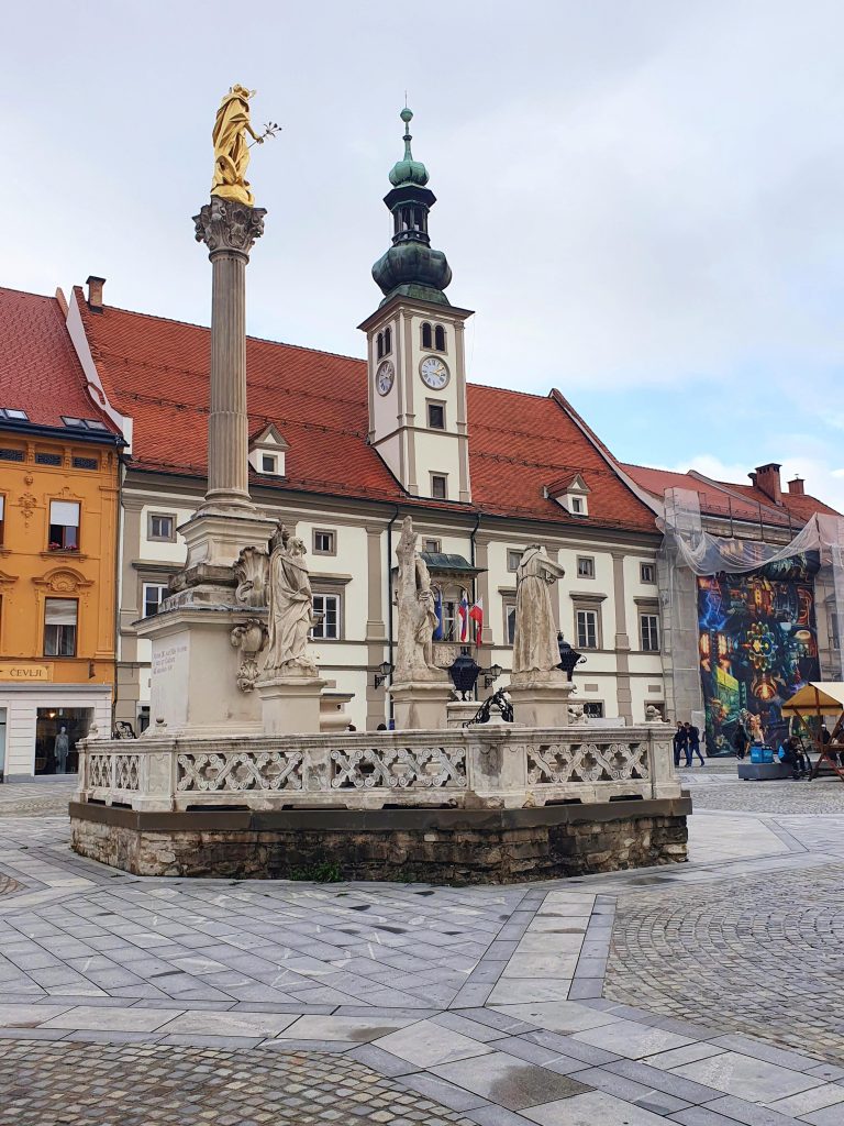 Pestsäule in einer Altstadt mit Brunnen